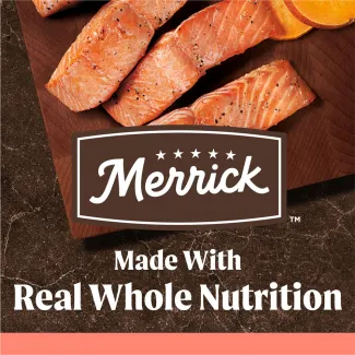 Slices of cooked salmon and sweet potatoes are presented on a dark wooden cutting board with the Merrick logo overlaid; Text reads "Made with Real Whole Nutrition"